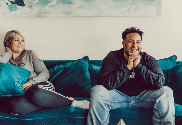 Two people smiling while lounging on a couch